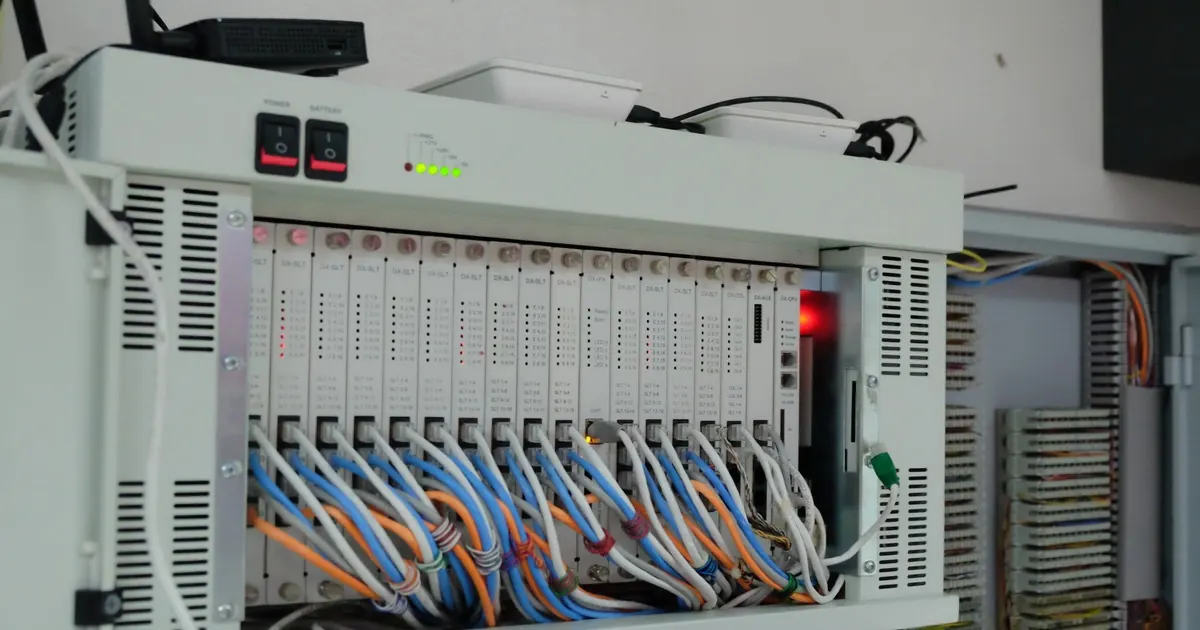 A telecoms equipment cabinet with line cards, indicator lights and bundles of blue and orange patch cables