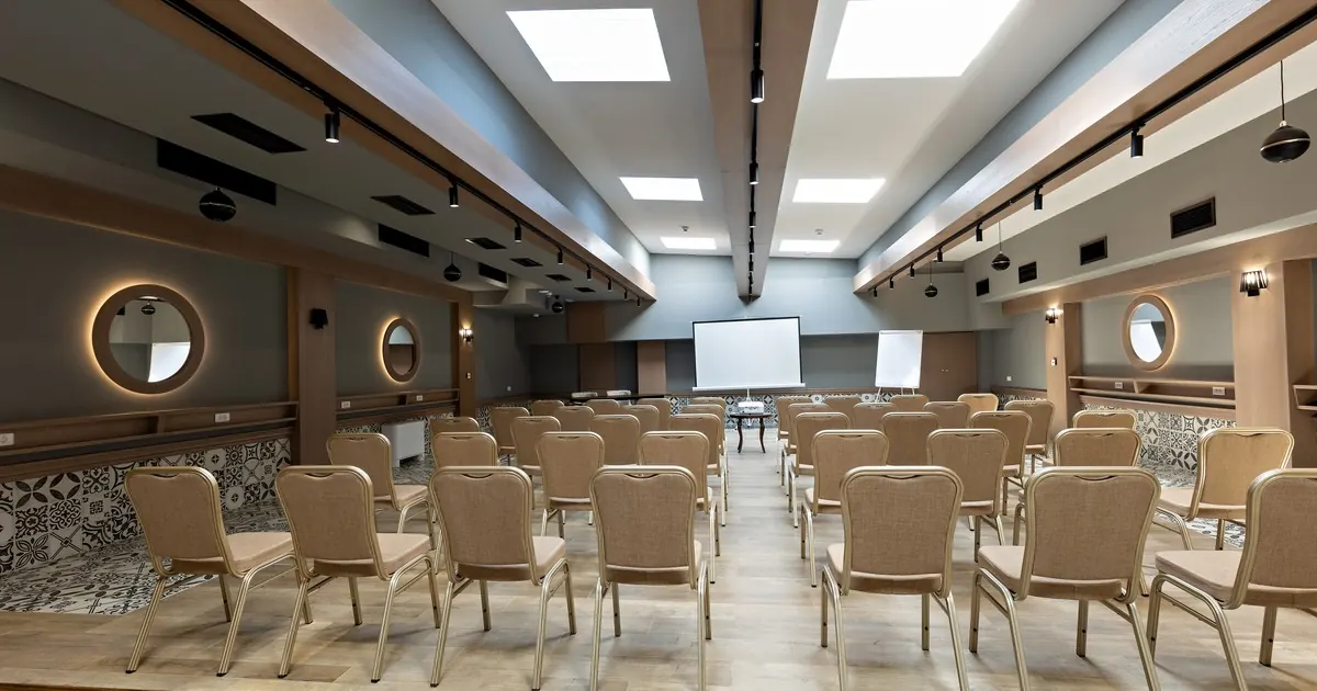 Rows of empty banquet chairs facing a projector screen and flipchart in a seminar room
