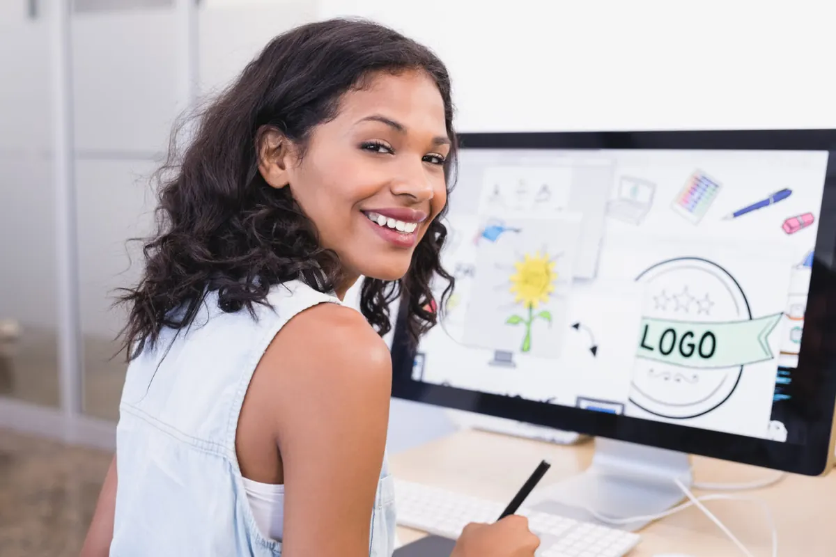 Designer reviewing logo concepts on a tablet and computer display